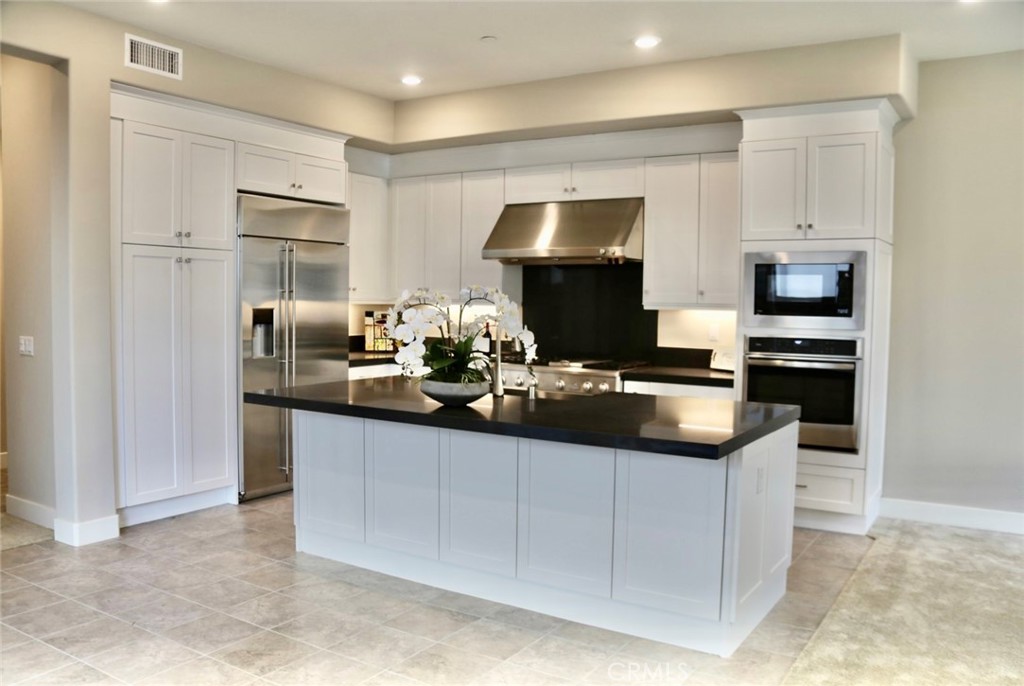 a kitchen with kitchen island granite countertop appliances cabinets and a counter space