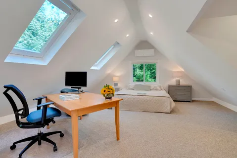 a bed sitting in a bedroom and table flat screen tv