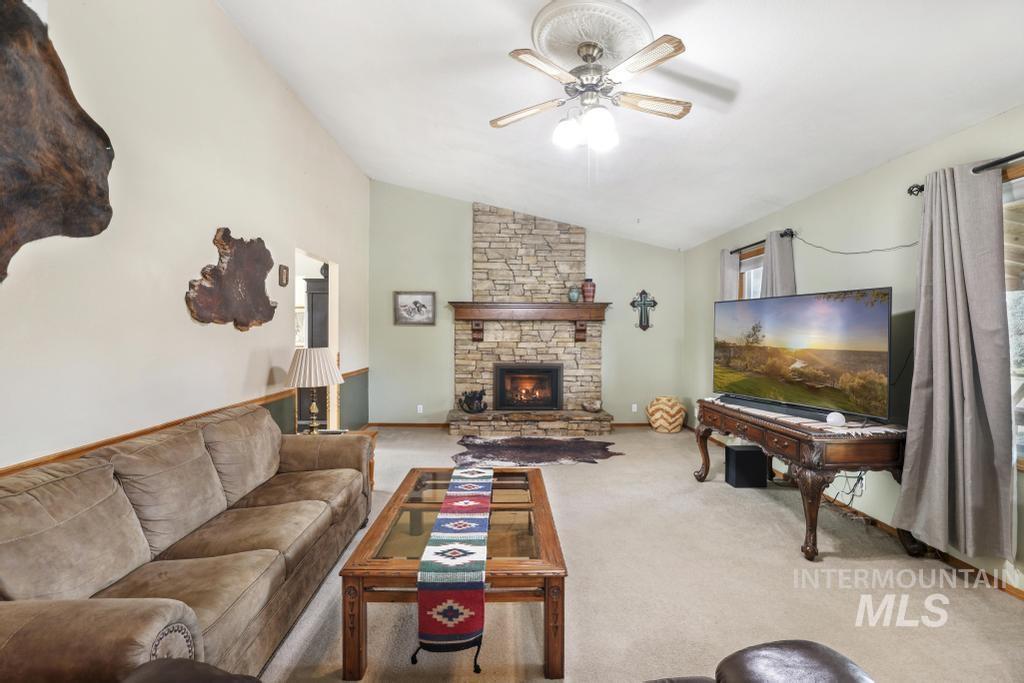 213 Sage Road West Jerome, ID 83338 - Photo 19 of 50 Carpeted living room featuring lofted ceiling, a fireplace, and a ceiling fan