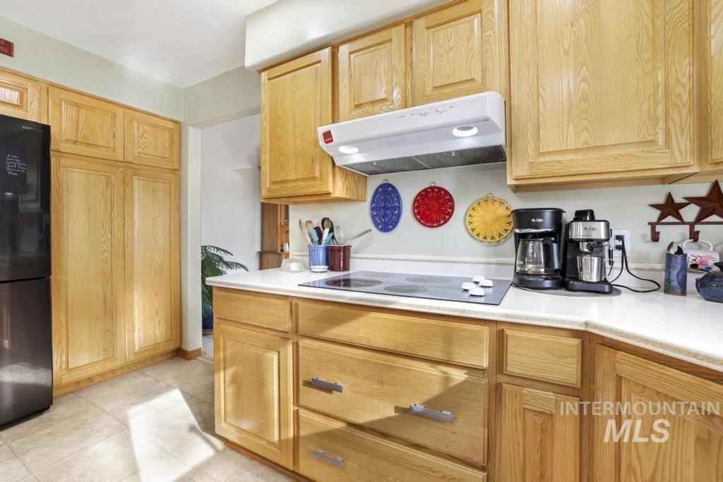 213 Sage Road West Jerome, ID 83338 - Photo 21 of 50 Kitchen with under cabinet range hood, black appliances, light countertops, and light brown cabinets