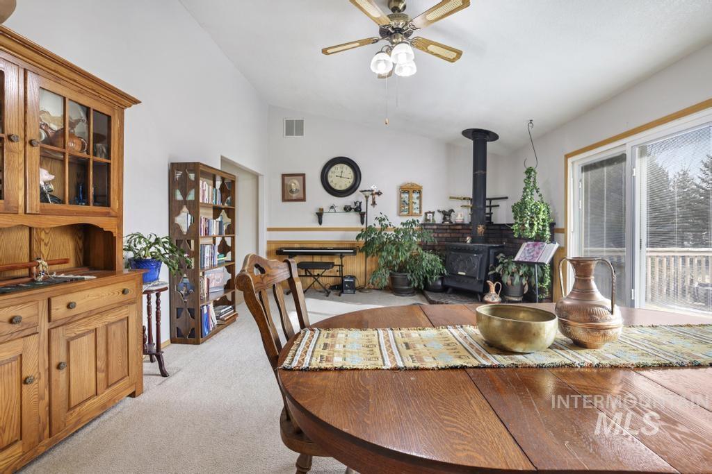 213 Sage Road West Jerome, ID 83338 - Photo 23 of 50 Dining room with a wood stove, lofted ceiling, light carpet, and ceiling fan