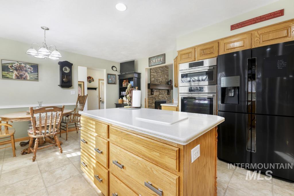 213 Sage Road West Jerome, ID 83338 - Photo 10 of 50 Kitchen featuring black fridge, a center island, light countertops, stainless steel double oven, and decorative light fixtures