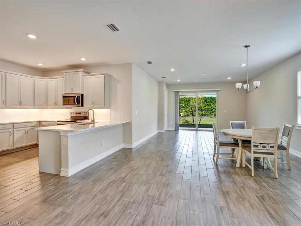 a kitchen with a sink wooden floor dining table chairs and a refrigerator