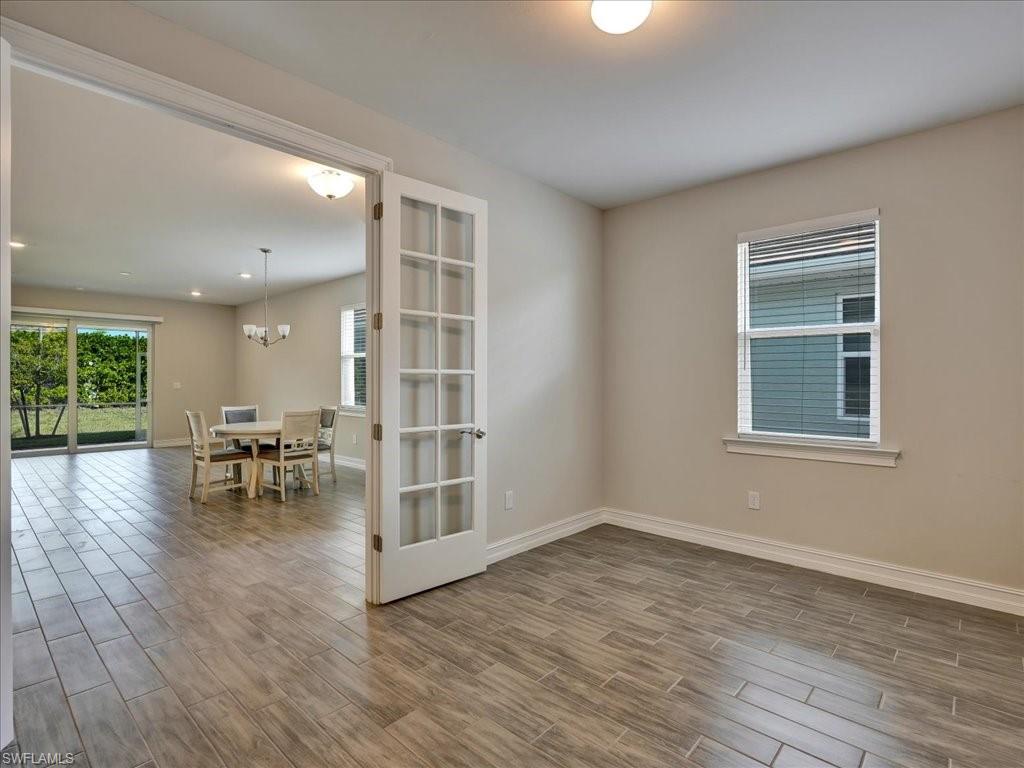 999 Enbrook Loop Naples, FL 34114 - Photo 14 of 50 a view of empty room with wooden floor and floor to ceiling window
