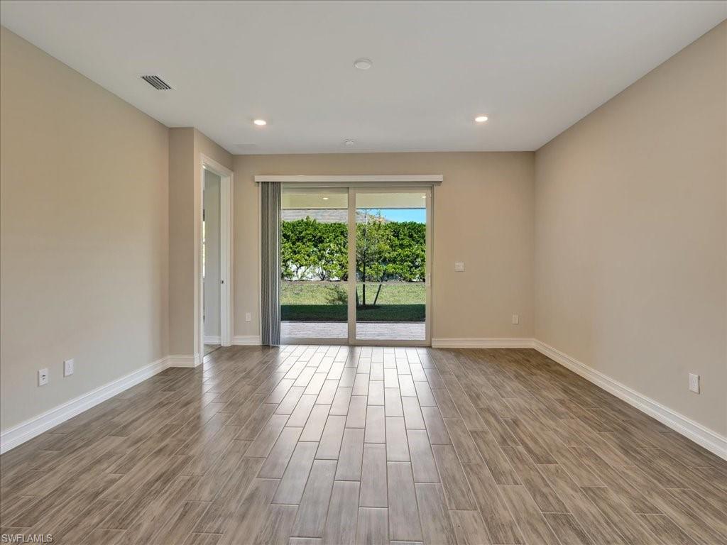 999 Enbrook Loop Naples, FL 34114 - Photo 5 of 50 a view of an empty room with wooden floor and a window