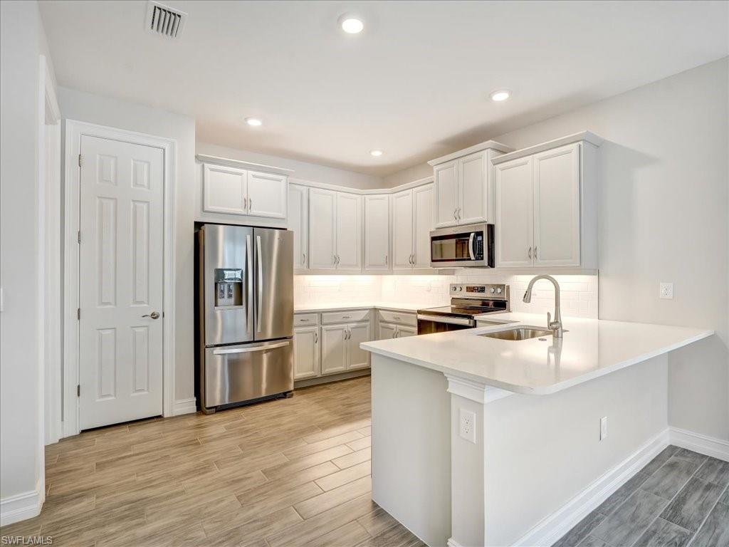 999 Enbrook Loop Naples, FL 34114 - Photo 7 of 50 a kitchen with refrigerator cabinets and wooden floor