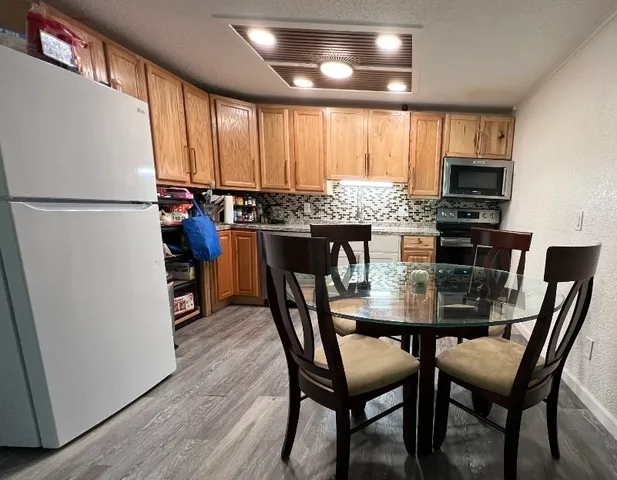 a kitchen with stainless steel appliances granite countertop a dining table chairs refrigerator and sink