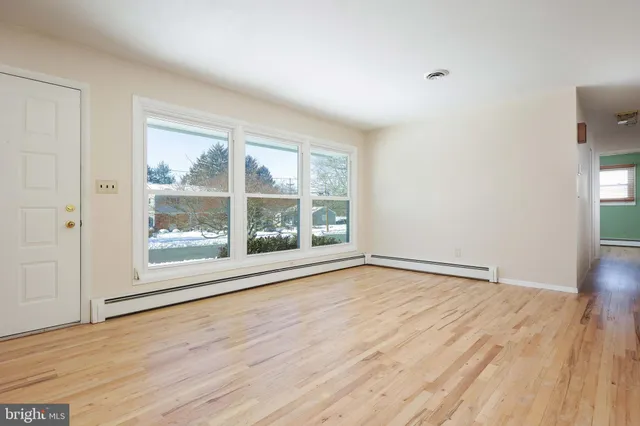 a view of an empty room with wooden floor and a window
