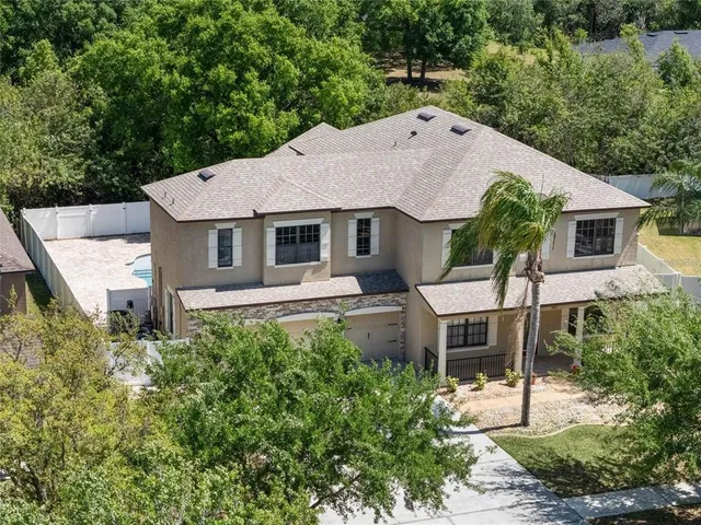 a aerial view of a house with a yard and large tree