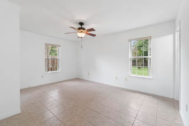 an empty room with windows and ceiling fan
