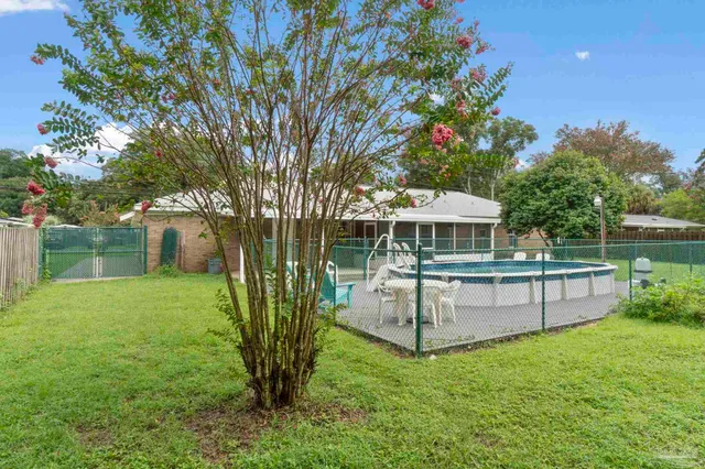 a view of a backyard with table and chairs and large tree