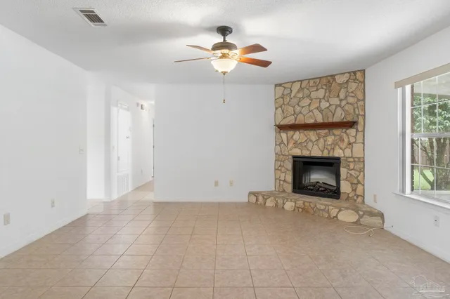wooden floor in an empty room with a fireplace and a window