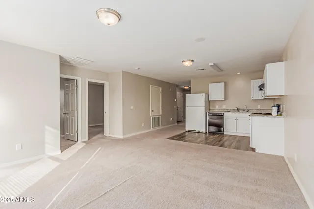 a view of kitchen with refrigerator and white cabinets