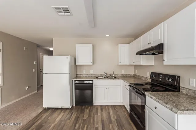 a kitchen with a refrigerator a stove top oven a sink and cabinets