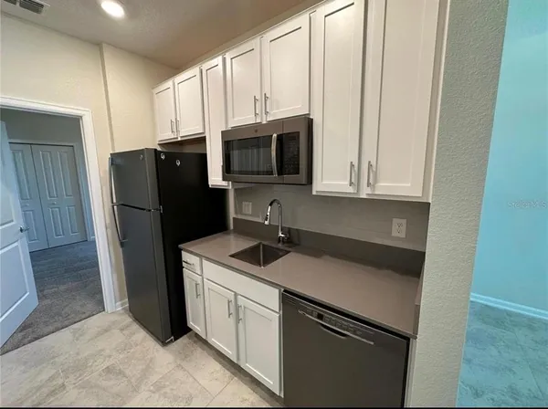 a kitchen with stainless steel appliances granite countertop a refrigerator a stove a microwave and a sink