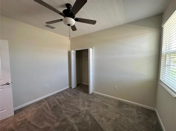 an empty room with a window and a fan