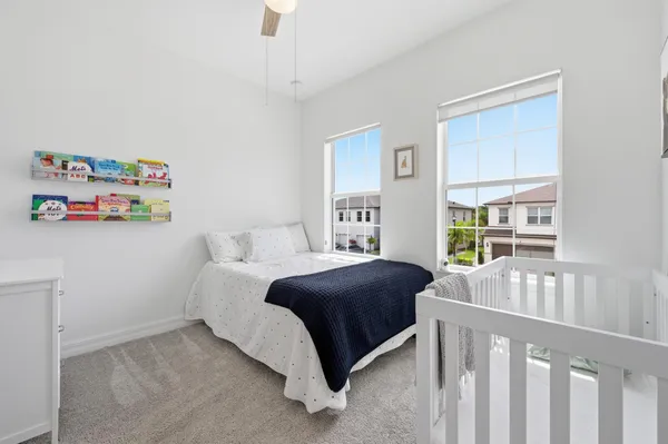 a bedroom with a bed a dresser and a large window