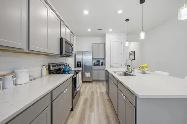 a kitchen with kitchen island granite countertop stainless steel appliances lots of counter space sink refrigerator and cabinets