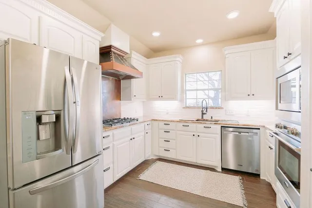 a kitchen with white cabinets and stainless steel appliances