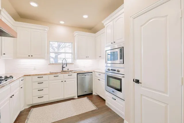 a kitchen with granite countertop white cabinets white stainless steel appliances with a sink and dishwasher