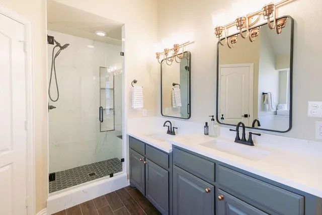a bathroom with a double vanity sink a mirror a glass door a shower and vanity