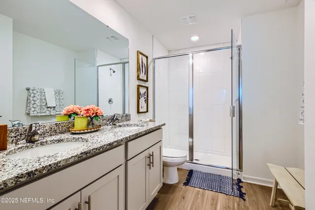 a bathroom with a granite countertop sink a toilet a mirror and shower