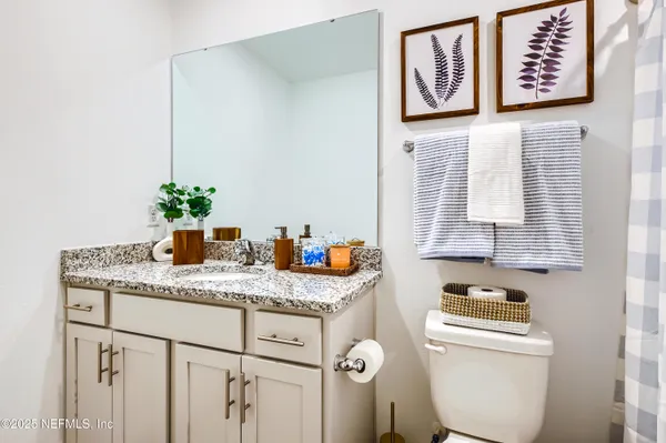 a bathroom with a granite countertop sink a toilet and a mirror