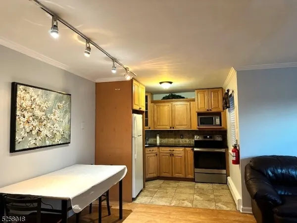 a kitchen with stainless steel appliances kitchen island granite countertop a stove a refrigerator a sink a dining table and chairs with wooden floor