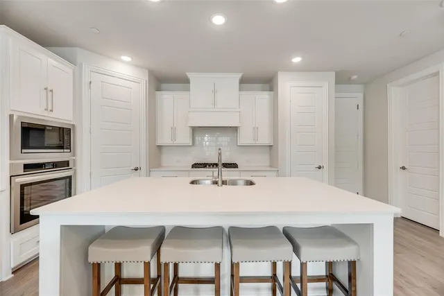 a kitchen with stainless steel appliances a table chairs microwave and cabinets