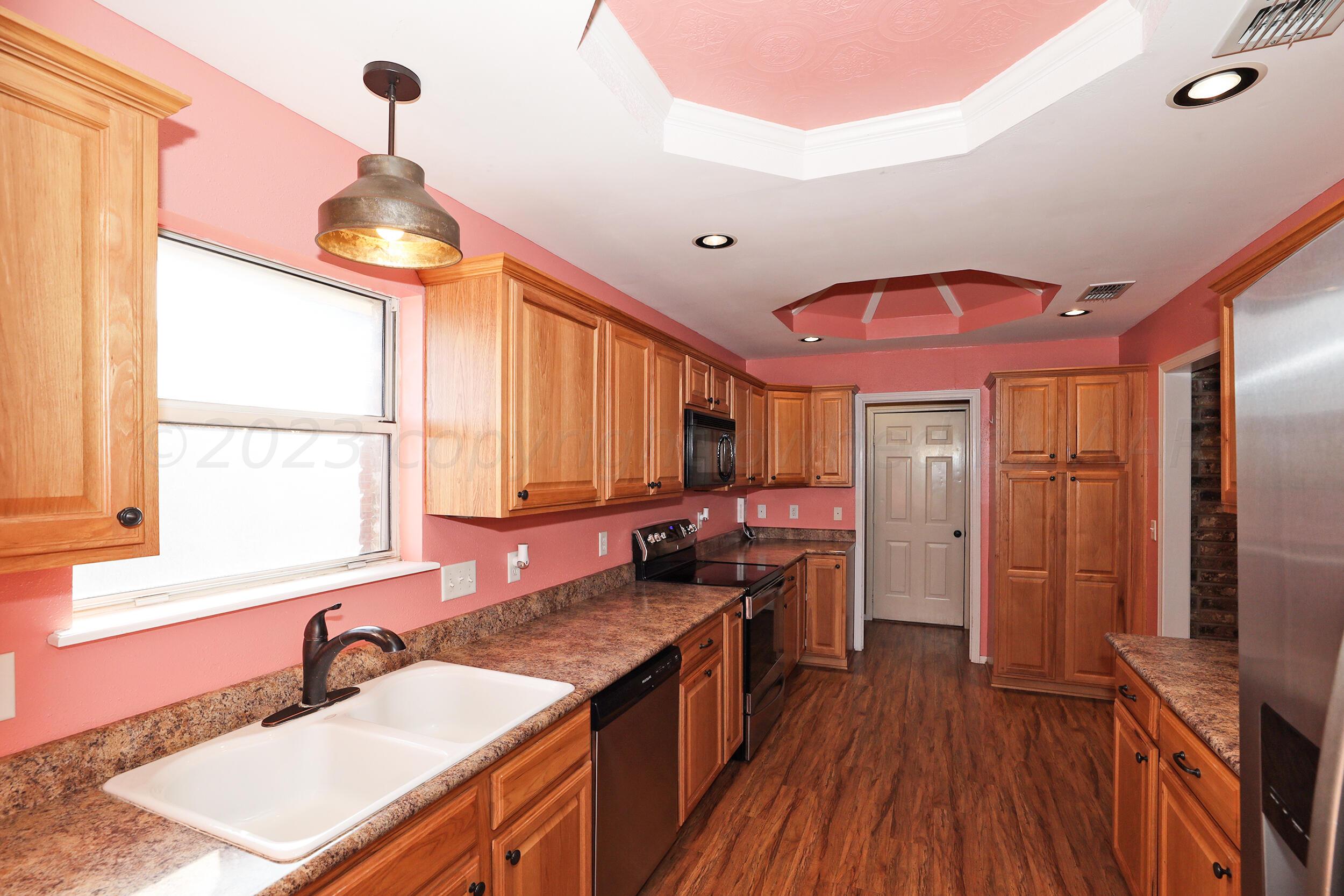 4207 Rincon Avenue Amarillo, TX 79110 - Photo 6 of 26 a kitchen with stainless steel appliances granite countertop a sink a stove and a wooden floors
