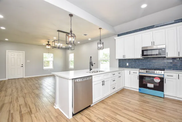 a large kitchen with stainless steel appliances granite countertop a stove and cabinets