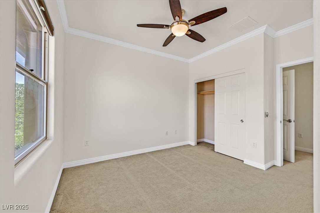 31 Via Mantova, Unit 2 Henderson, NV 89011 - Photo 17 of 30 Unfurnished bedroom featuring crown molding, carpet, ceiling fan, and a closet