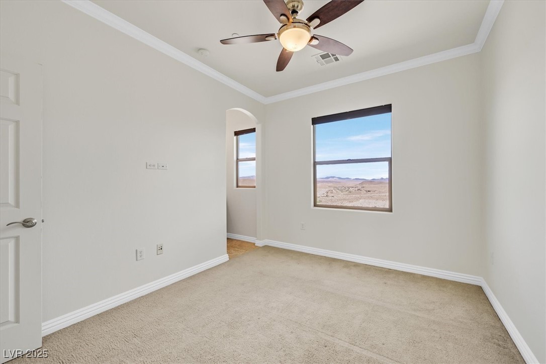 31 Via Mantova, Unit 2 Henderson, NV 89011 - Photo 18 of 30 Empty room with ornamental molding, light carpet, a ceiling fan, and arched walkways