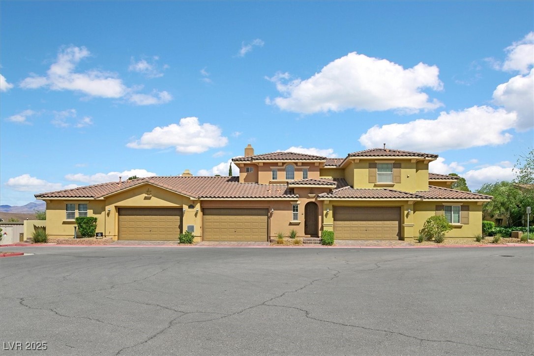 31 Via Mantova, Unit 2 Henderson, NV 89011 - Photo 20 of 30 Mediterranean / spanish-style home featuring stucco siding, a chimney, a tile roof, driveway, and a garage