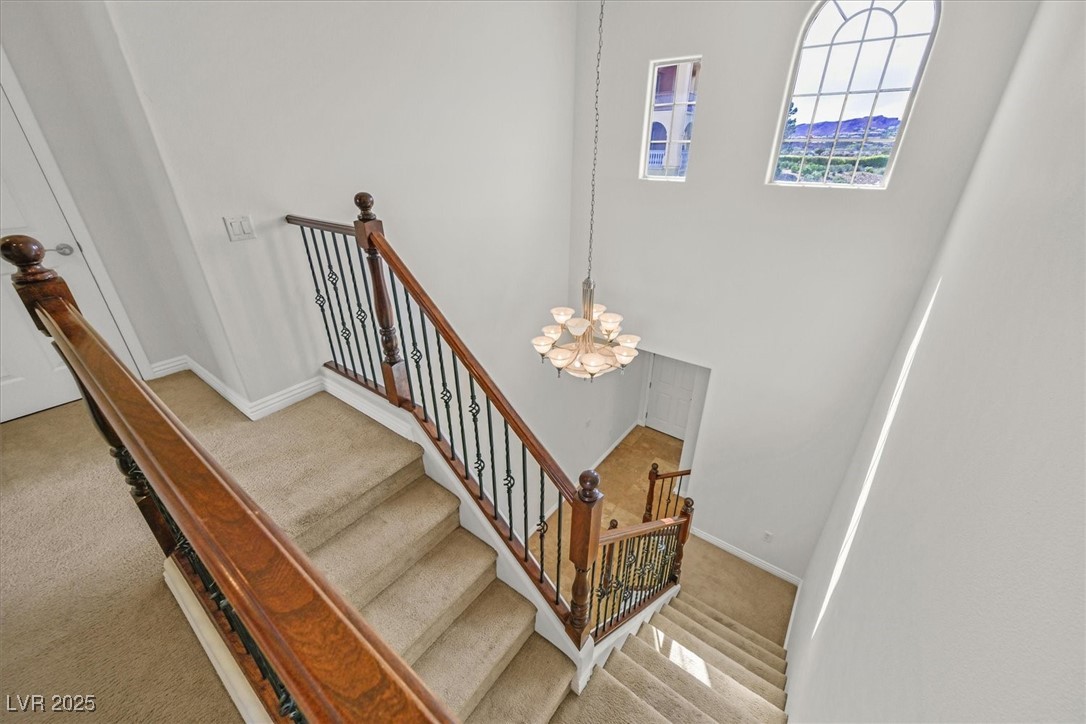 31 Via Mantova, Unit 2 Henderson, NV 89011 - Photo 9 of 30 Stairs featuring carpet, a chandelier, and a high ceiling