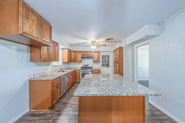 a large kitchen with kitchen island a large counter top space and stainless steel appliances