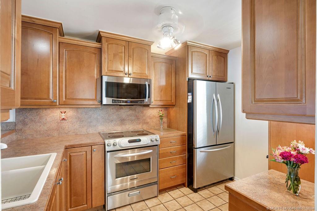 1950 Southwest Palm City Road, Unit 14302 Stuart, FL 34994 - Photo 12 of 62 a kitchen with granite countertop a refrigerator stove and microwave