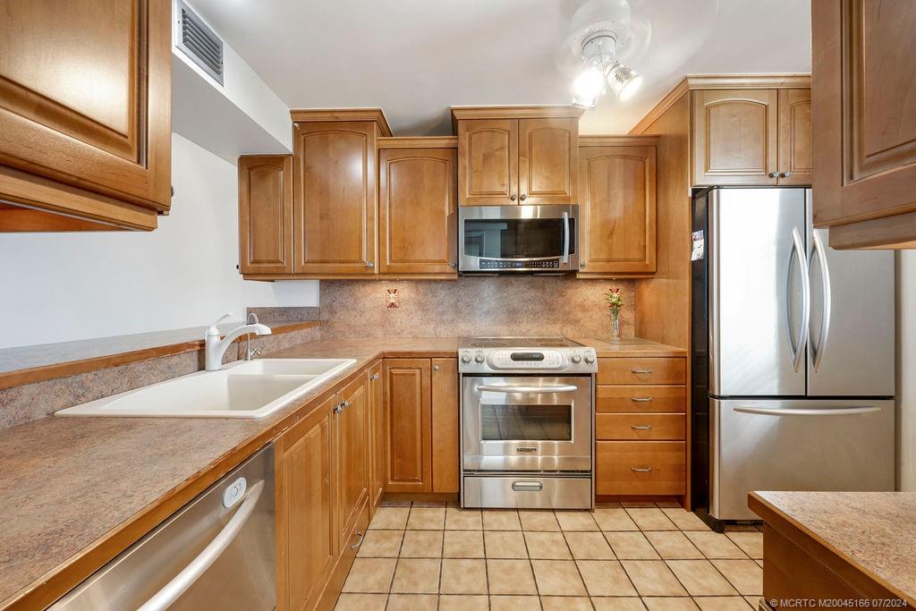 1950 Southwest Palm City Road, Unit 14302 Stuart, FL 34994 - Photo 13 of 62 a kitchen with stainless steel appliances granite countertop a refrigerator a sink and a stove