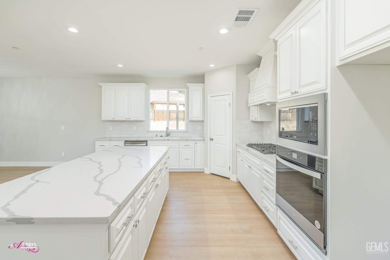 Undisclosed Address Bakersfield, CA 93306 - Photo 14 of 51 a large white kitchen with stainless steel appliances granite countertop a lot of counter space and wooden floors