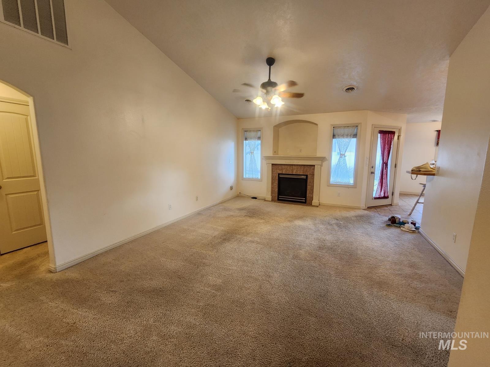 1000 North Rodeo Street Parma, ID 83660 - Photo 11 of 35 Unfurnished living room featuring lofted ceiling, light carpet, ceiling fan, and a fireplace