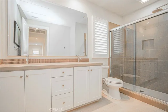 a bathroom with a double vanity sink a toilet and a shower