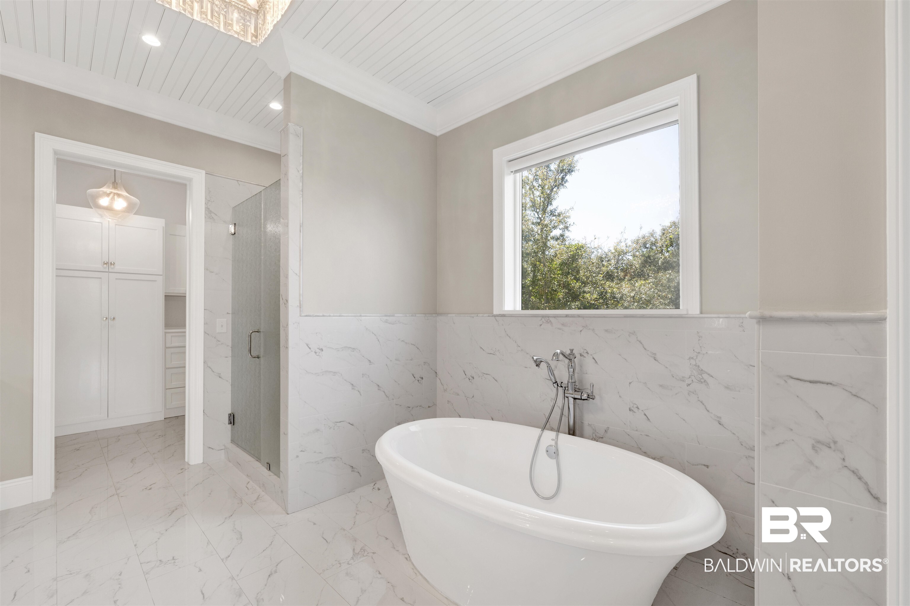 31729 River Road Orange Beach, AL 36561 - Photo 28 of 54 Bathroom with light marble finish flooring, a marble finish shower, a freestanding tub, wainscoting, and crown molding