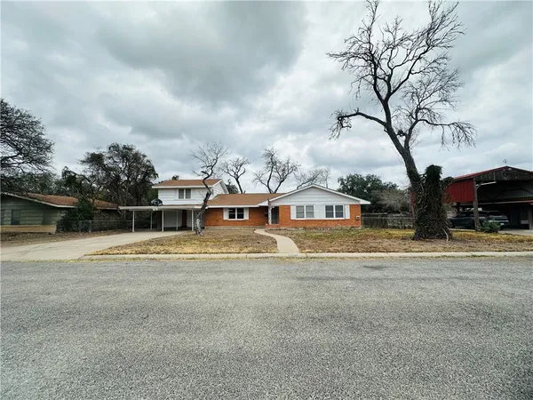 a view of big house with a big yard and large trees