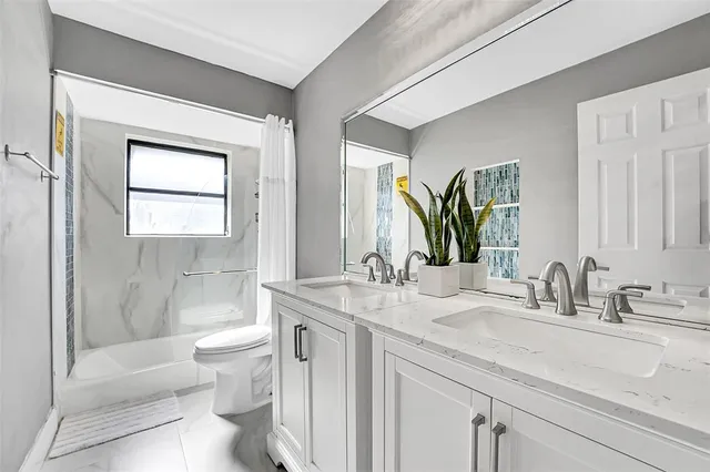 a bathroom with a double vanity sink toilet and shower
