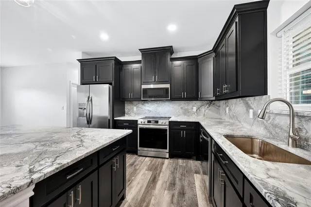 a kitchen with stainless steel appliances granite countertop a sink stove and refrigerator