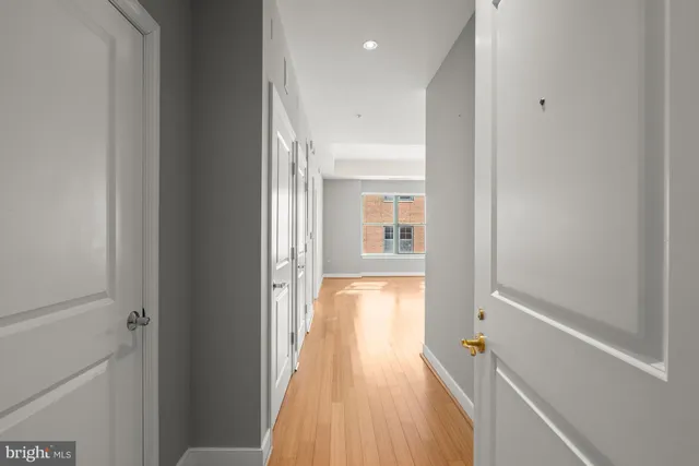 a view of a hallway with wooden floor and a bathroom