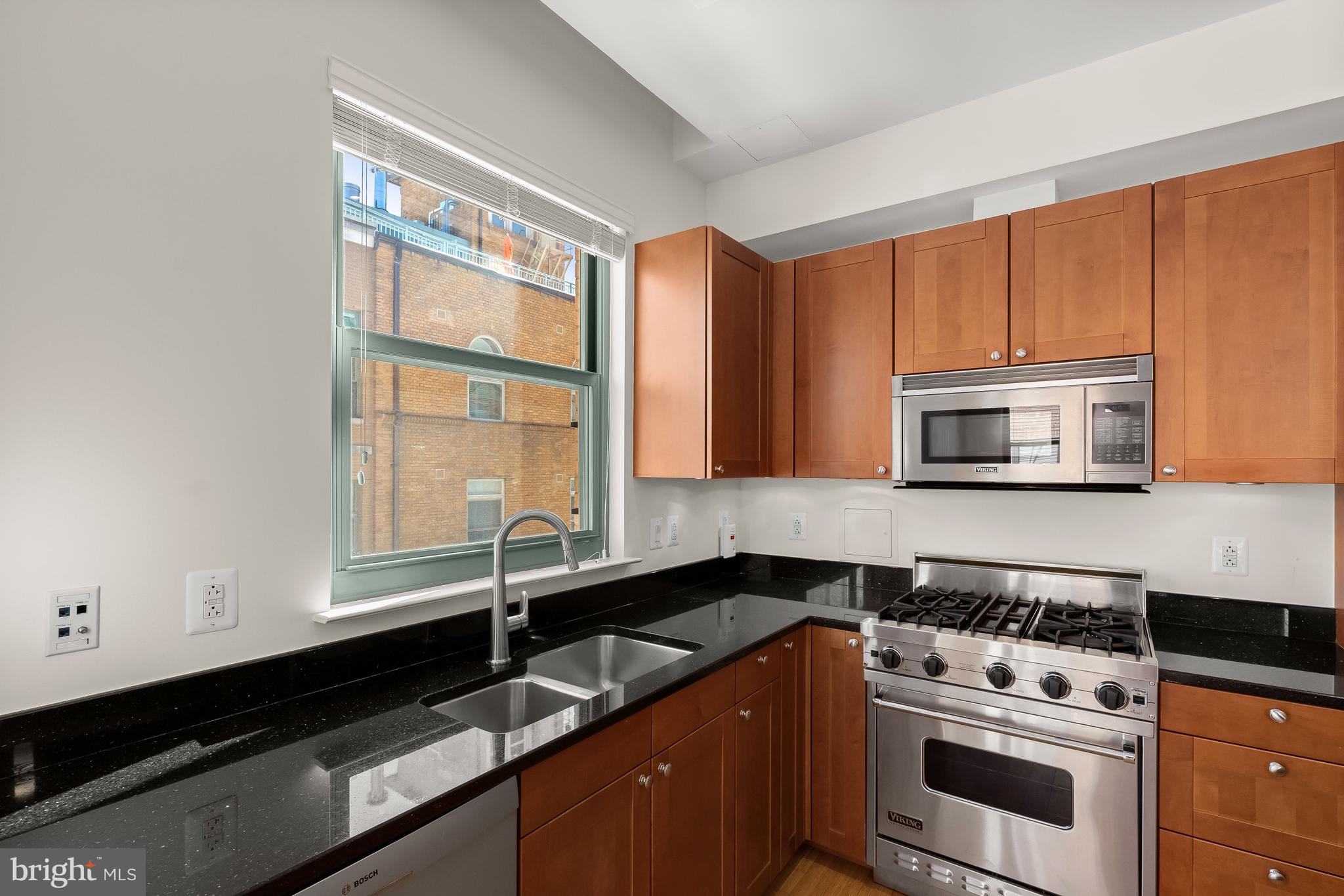 2425 L Street Northwest, Unit 709 Washington, DC 20037 - Photo 9 of 24 a kitchen with granite countertop a sink a stove and cabinets