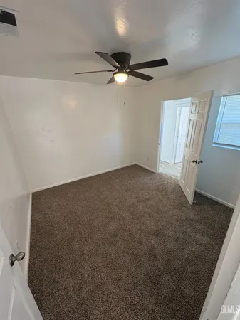 a view of an empty room with a ceiling fan and window