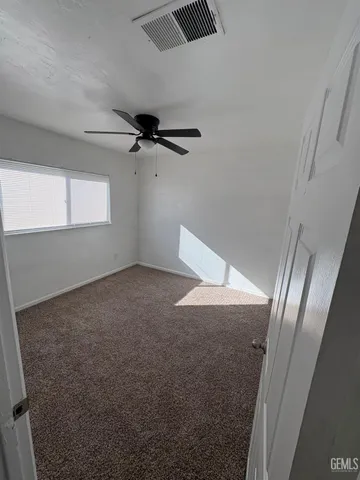 an empty room with a ceiling fan and window