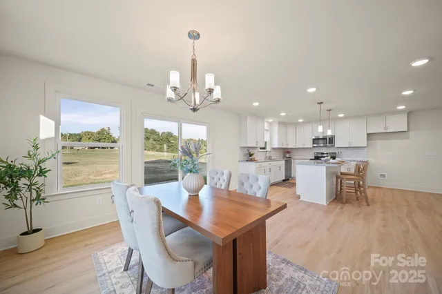 a view of a dining room and livingroom with furniture wooden floor a chandelier